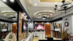 Un lobby de hotel moderno con un área de estar central, una chimenea y un muro decorativo.