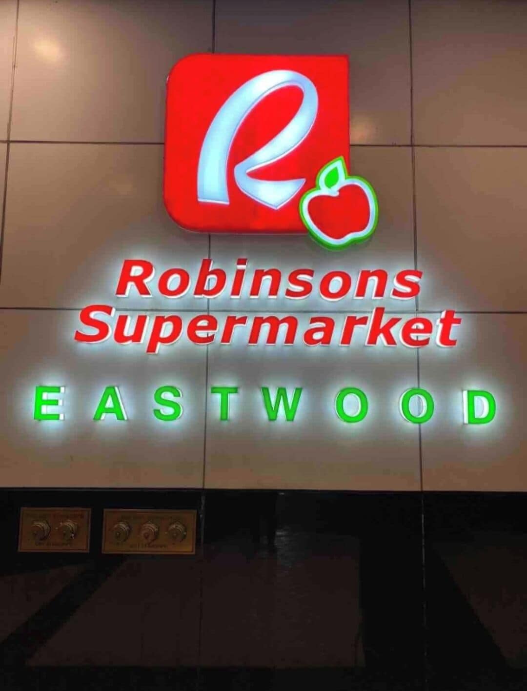 A sign for Robinsons Supermarket Eastwood with a logo and the name in red and green letters.