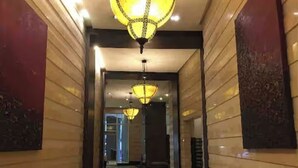 Un pasillo con candelabros, paneles de madera y suelo de mármol.