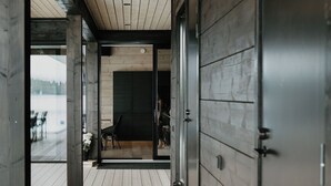 Un couloir au plancher en bois mène à une pièce dotée d’une grande fenêtre, d’une porte et offrant une vue sur l’extérieur.