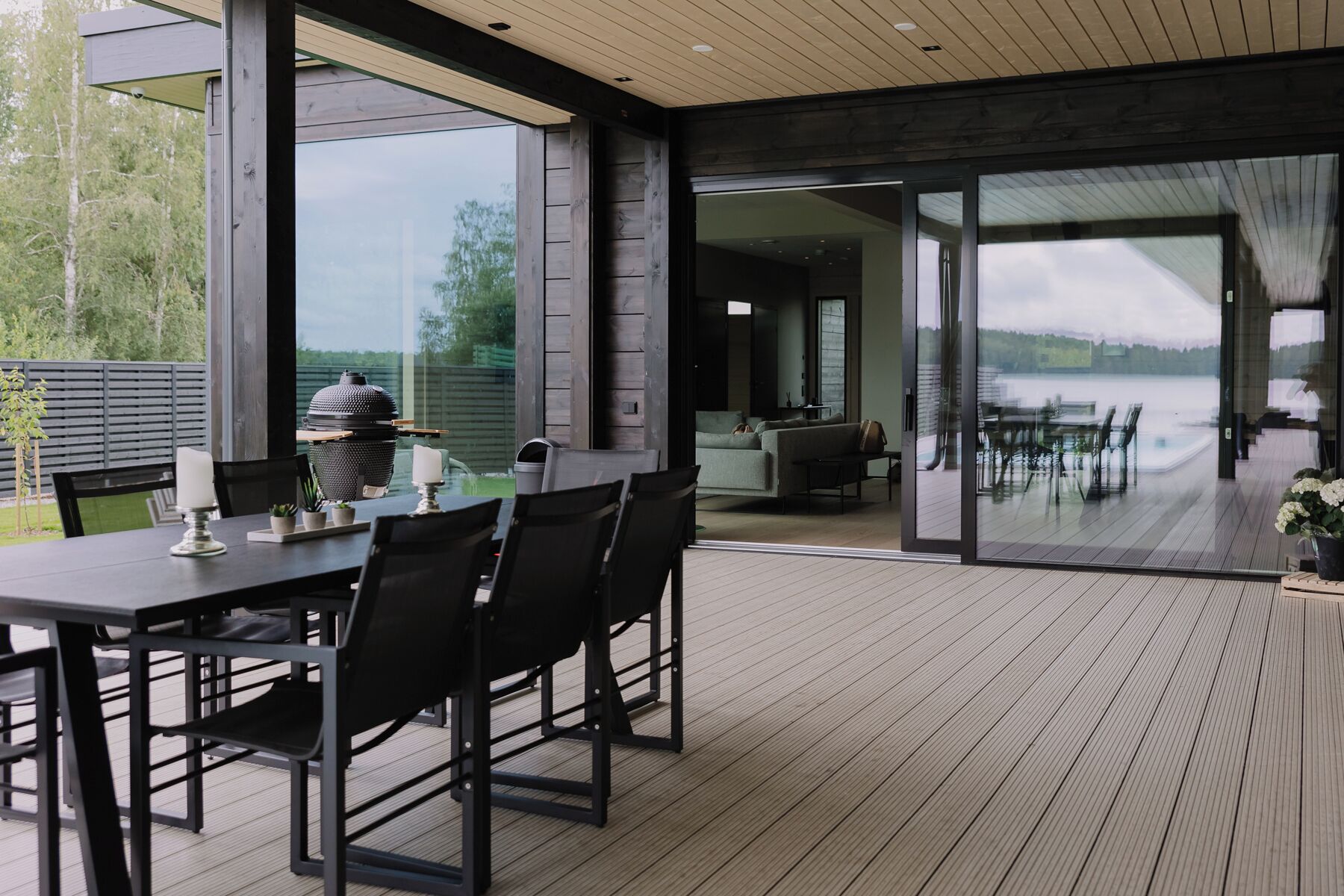 Un espacio moderno para comer al aire libre con una terraza de madera, una parrilla y vistas a un lago.