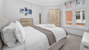 A bedroom with a bed, a wooden headboard, a window with a view, and artwork on the wall.