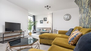A modern living room with a sofa, a coffee table, and a flat-screen TV.