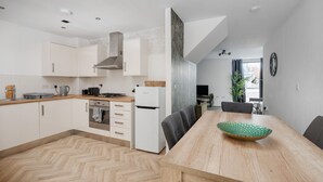 A modern kitchen with white cabinets, a wooden countertop, and a dining area with a wooden table and chairs.
