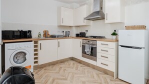 A compact kitchen with a washing machine, microwave, stove, oven, and a refrigerator.
