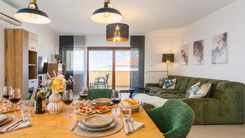 A modern dining area with a wooden table set for a meal, a green sofa, and pendant lighting.
