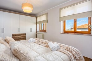 Una camera da letto con un letto, un armadio, un termosifone e una finestra con vista.