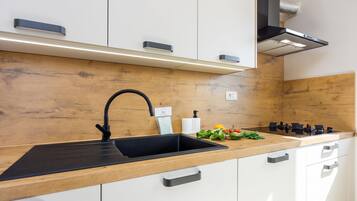 A modern kitchen with a black sink, stainless steel appliances, and wooden cabinetry.