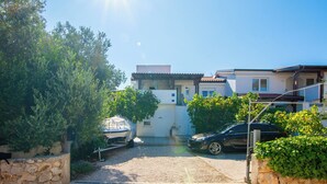 Zona residencial con una casa, un coche aparcado y una barca cubierta con un toldo.