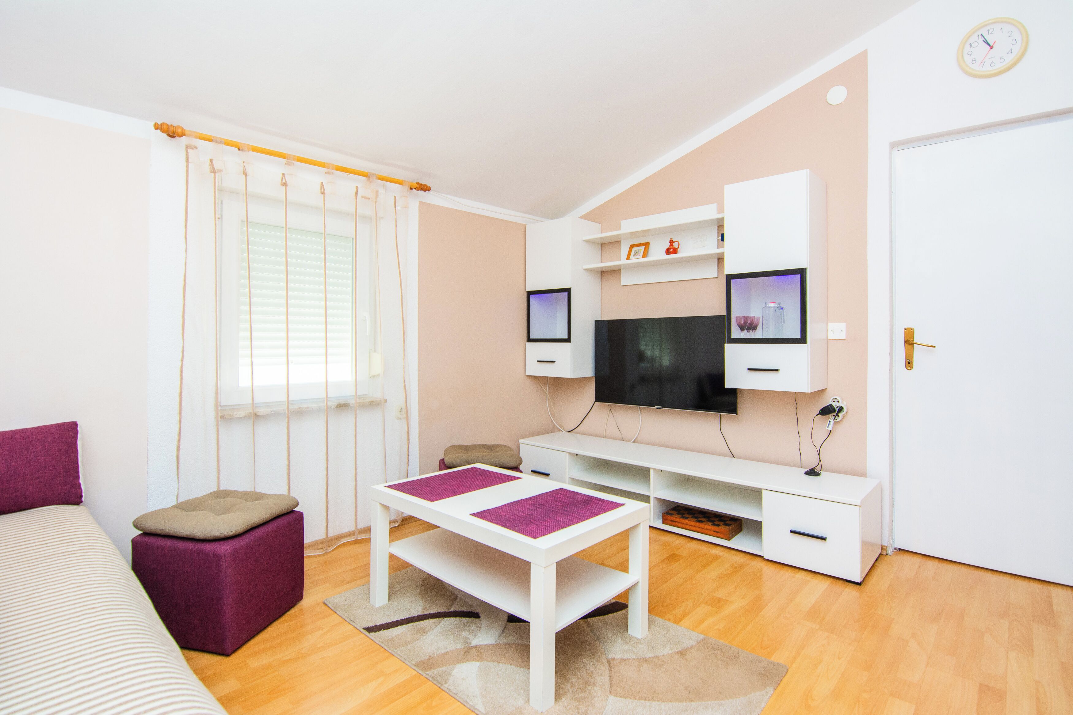 A modern living room with a flat-screen TV, a sofa, a coffee table, and a television on a shelf.