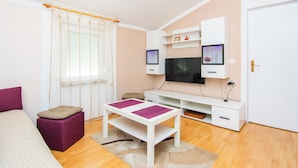 Una sala de estar moderna con un sofá, una mesa de centro, un televisor y un mueble blanco para televisión.