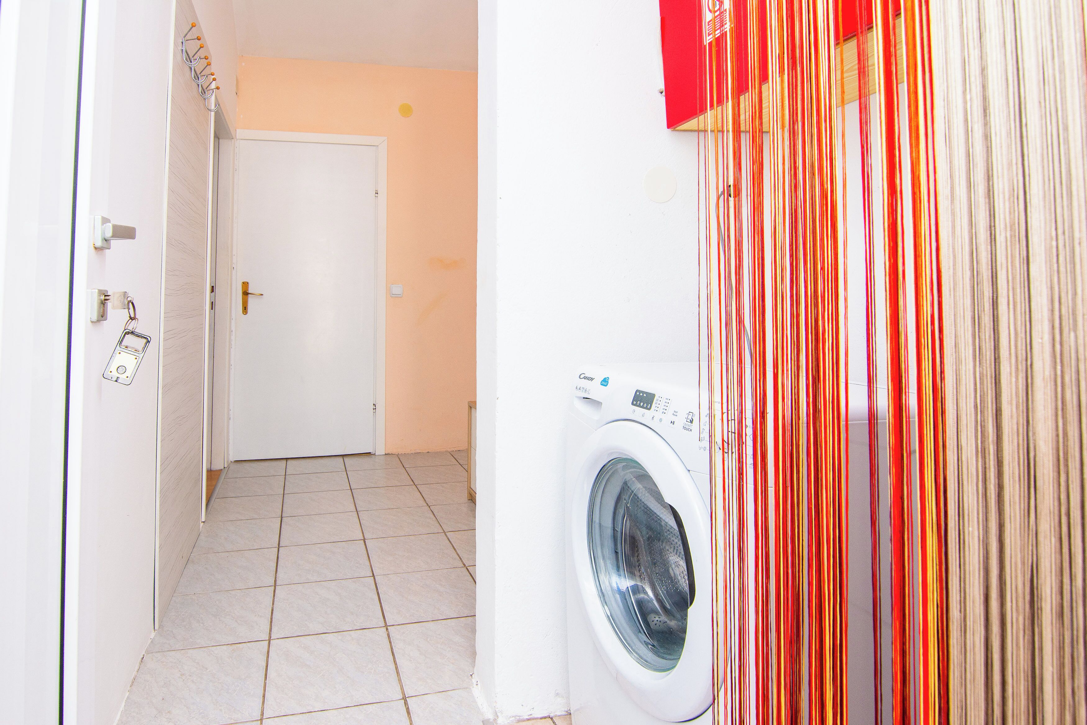 Une buanderie équipée d’un lave-linge, d’une porte et d’un sol carrelé.