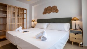 A neatly made bed with white linens, a wooden wardrobe, and a wall-mounted decorative piece. - A040 PEÑON DE IFACH 6º A (Calp)