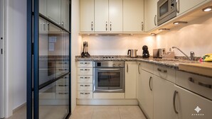 A modern kitchen with white cabinets, stainless steel appliances, and a granite countertop. - A040 PEÑON DE IFACH 6º A (Calp)