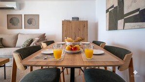 A dining area with a wooden table, green upholstered chairs, a fruit bowl, and glasses of orange juice. - A040 PEÑON DE IFACH 6º A (Calp)