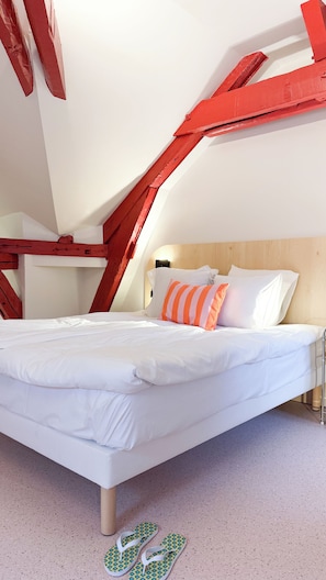 Un dormitorio con cama, almohadas y un par de pantuflas en el suelo.