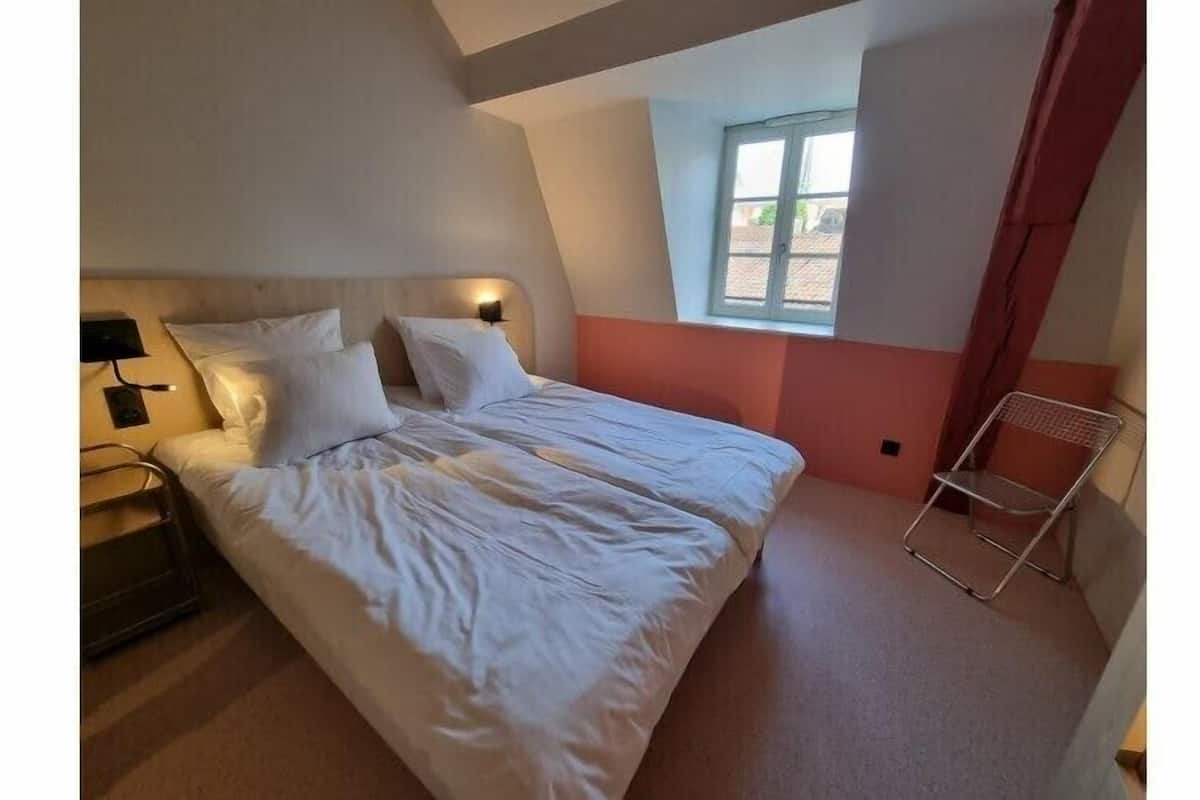 Ein Schlafzimmer mit Bett, Nachttisch, Lampe und Fenster.