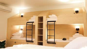 A bunk bed room with built-in shelves and bedside lamps.