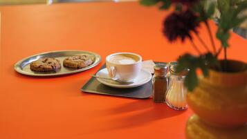 A table with a cup of coffee, a plate of cookies, and a salt shaker.