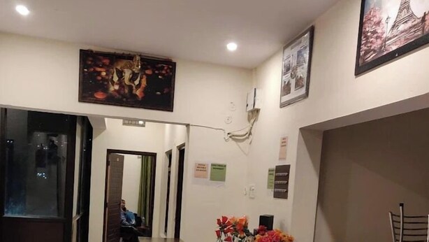 A reception area with a reception desk, two red chairs, a small table, and a ceiling fan. - Hotel Dev Darshan & Restaurant (Bhatwari)