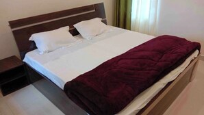 A bed with a wooden headboard, white bedding, and a dark red blanket. - Hotel Dev Darshan & Restaurant (Bhatwari)