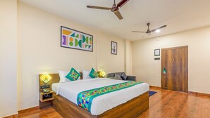 Quarto de hotel com cama de madeira, ventoinha no teto, guarda-roupa de madeira e quadro emoldurado na parede.