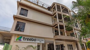 Um edifício de vários andares com uma placa indicando 'treebo Green Pearl Inn'.