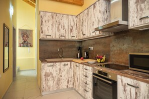 A kitchen with wooden cabinets, a stainless steel range hood, and a microwave. - Sirius House (Mitilinii)