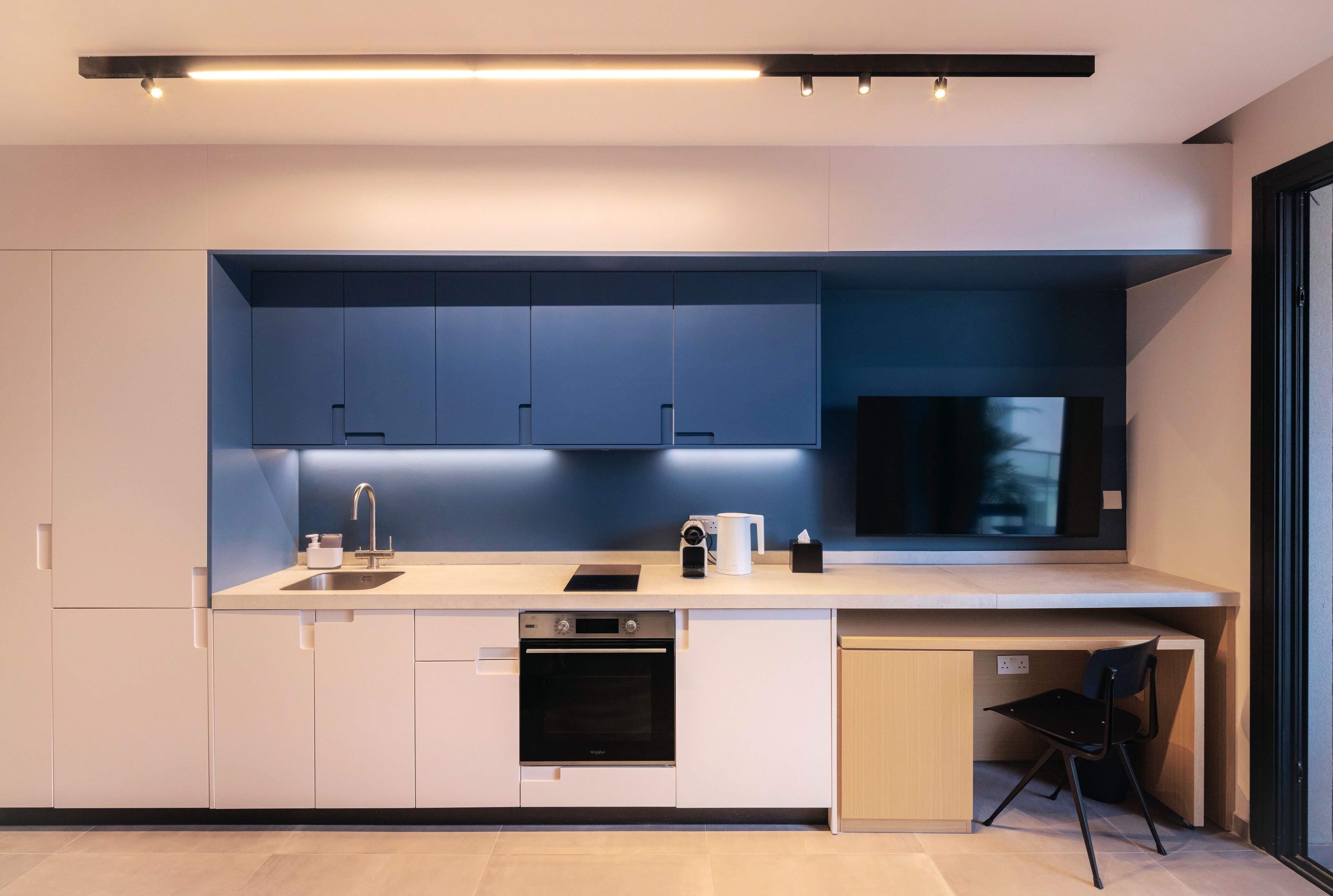 A modern kitchen with a built-in oven, a sink, and a countertop with a coffee maker and a phone.