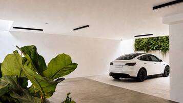 A modern, minimalist interior with a white car parked in a spacious, concrete-floored garage.