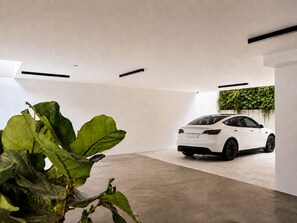 A modern, minimalist interior with a white car parked in a spacious, concrete-floored garage. - Aweso Limassol (Limassol)