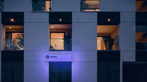 Ein modernes Gebäude mit einem Schild, auf dem 'Aveso' steht, und einem Glastür-Eingang.