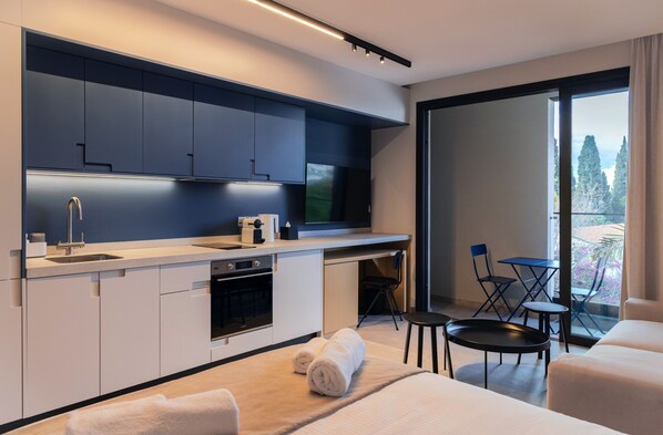 A modern kitchen with a built-in oven, a sink, and a dining area with a table and chairs. - Aweso Limassol (Limassol)