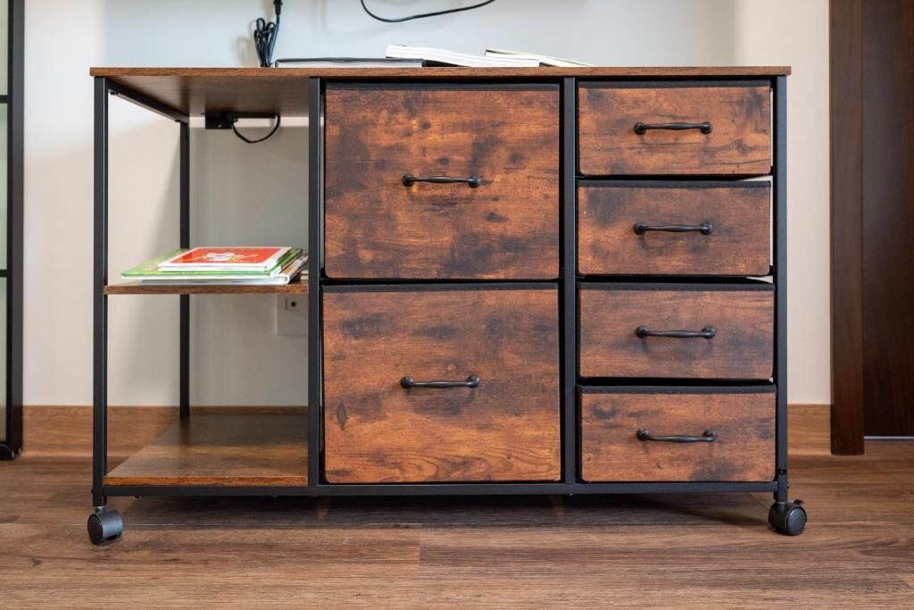 A wooden filing cabinet with drawers and a shelf, placed on wheels.