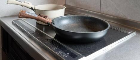 Una cocina con estufa, sartén y olla.