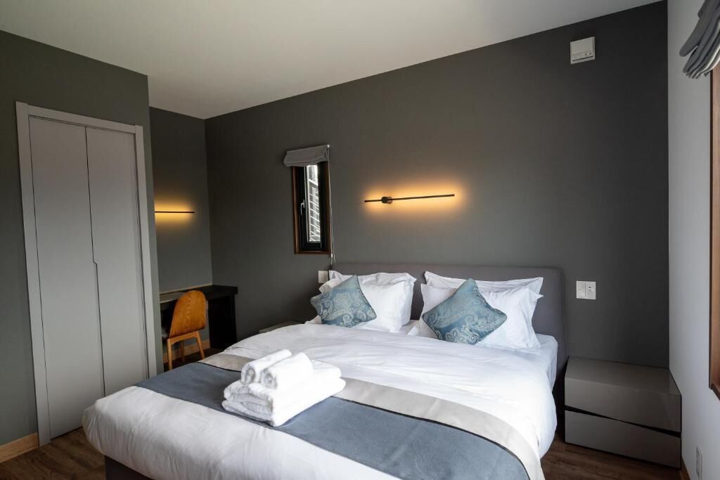 Et moderne hotelværelse med en stor seng, et natbord, en stol og et klædeskab.