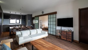 A modern living room with a sofa, coffee table, and a TV. There is a dining area with chairs and a table. - Furano Torinuma VILLA (Furano)