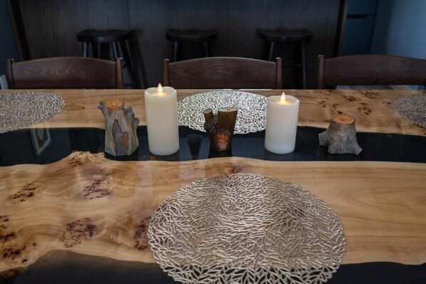 A dining table with a natural wood finish, two lit candles, and decorative wooden pieces.