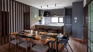 A modern kitchen with a central island, bar stools, and a dining table set for six. - Furano Torinuma VILLA (Furano)