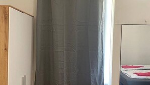 Une chambre à coucher avec un lit, une armoire et un rideau.
