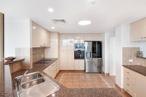 A modern kitchen with stainless steel appliances, a double sink, and light-colored cabinetry.
