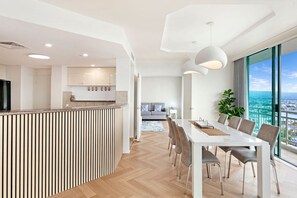 Een moderne keuken met een inbouw eiland, een eethoek met een lange tafel en stoelen, en een groot raam met uitzicht op de stad.