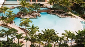 Een zwembadcomplex met diverse waterattracties, palmbomen en ligbedden.