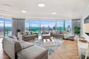 Een moderne woonkamer met een panoramisch stadsbeeld, ingericht met banken en een salontafel.