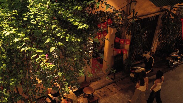 Een binnenplaats met een bank, tafels en potplanten.