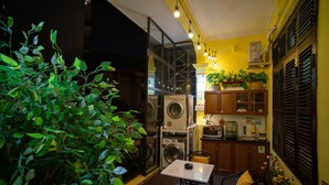 Een kleine keuken met een wasmachine, magnetron en houten keukenkastjes.