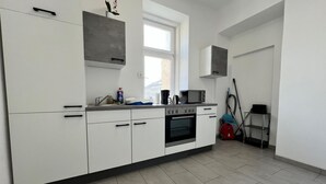 Eine moderne Küche mit weißen Schränken, einer Mikrowelle, einer Kaffeemaschine und einem roten Staubsauger.