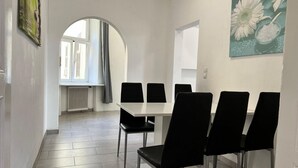Ein Essbereich mit einem weißen Tisch, schwarzen Stühlen, einem großen Fenster mit Aussicht und einem Gemälde an der Wand.