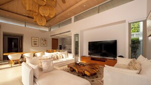 A spacious living room with a large flat-screen TV, white sofas, and a wooden coffee table. - Exclusive villa in Botanica The Nature (Choeng Thale)