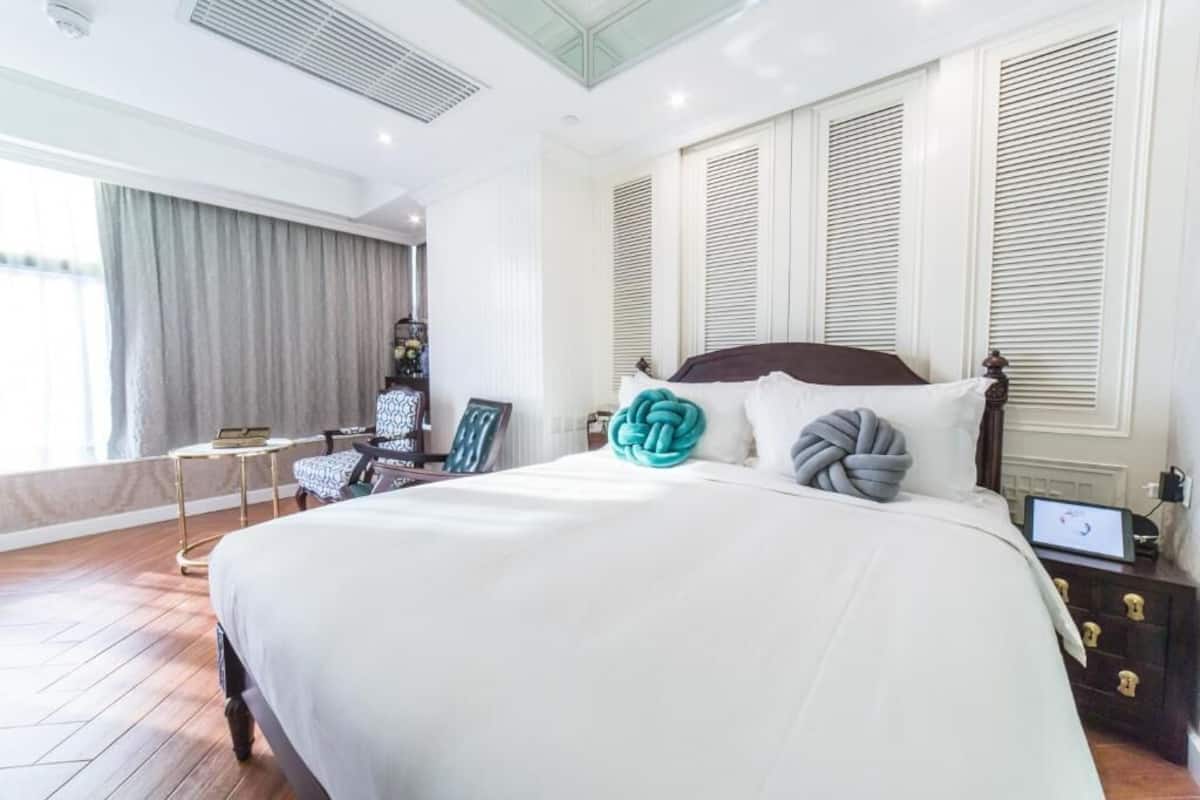A hotel room with a large bed, a bedside table, a chair, and a view of the outdoors.